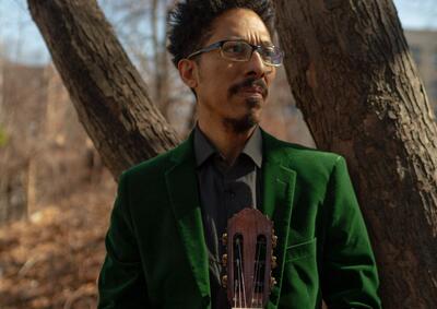 man in green suit holding guitar